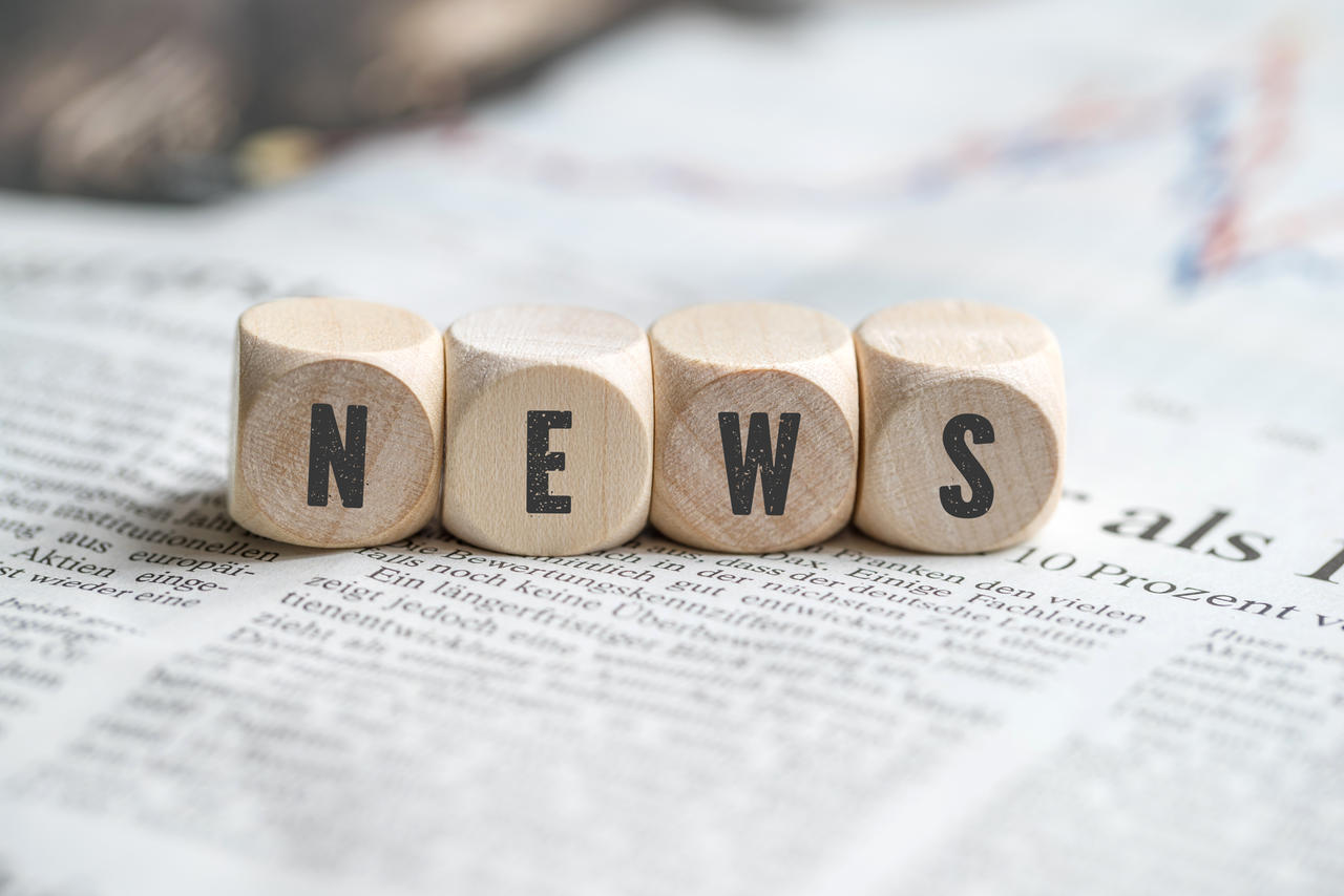 Würfel mit Aufschrift NEWS auf einer Zeitung