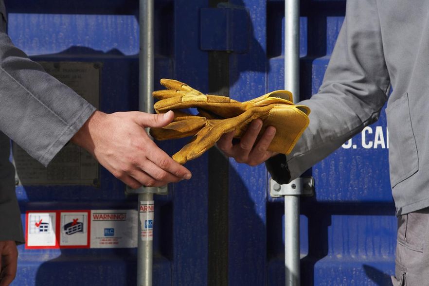 Arbeiter &uuml;bergeben Handschuhe