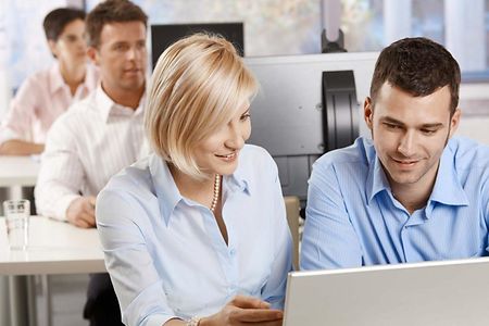 Eine Frau und ein Mann sehen auf einen Computerbildschirm.