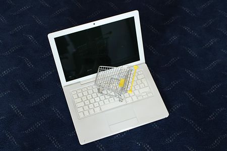 Spielzeug-Einkaufswagen steht auf einem Laptop 