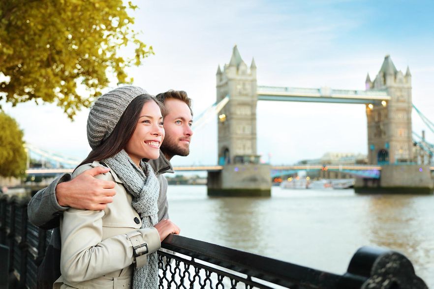 Ein junges Paar schaut in der N&auml;he der Tower Bridge &uuml;ber die Themse. 