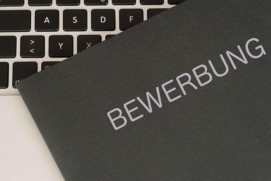 Der obere Teil einer Bewerbungsmappe mit der Aufschrift Bewerbung liegt auf einer Computertastatur