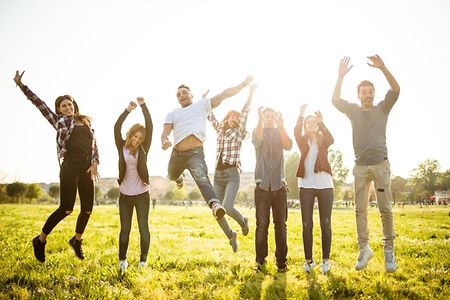 Group of people jumping on the park at dusk