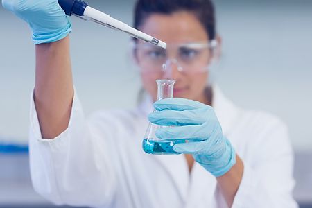 Labormitarbeiterin mit Pipette und Laborglas