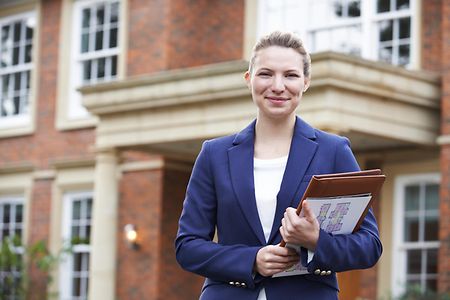 Portrait Of Female Realtor Standing Outside Residential Property