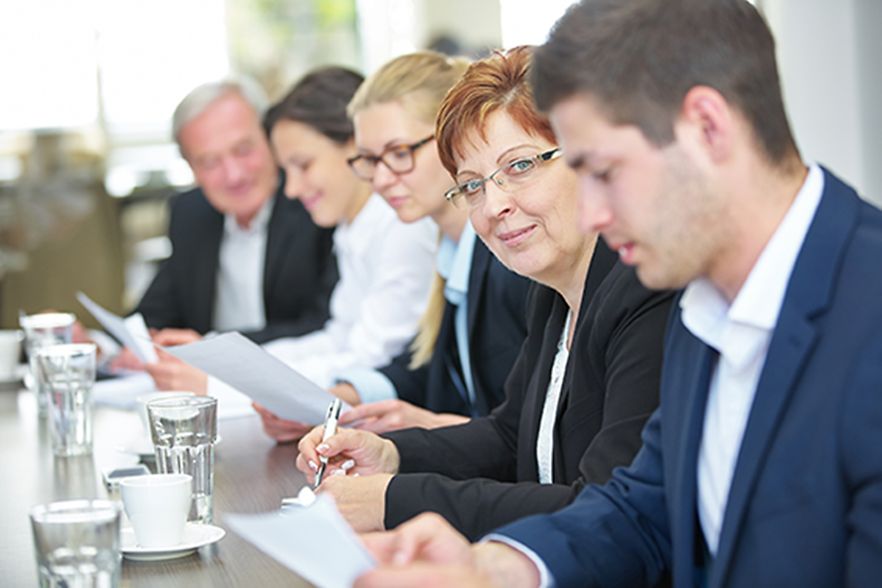 Gesch&auml;ftsleute bei einem Meeting, eine Frau schaut in die Kamera