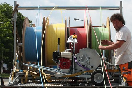 Ein Bauarbeiter rollt Glasfaserkabel von gro&szlig;en Rollen