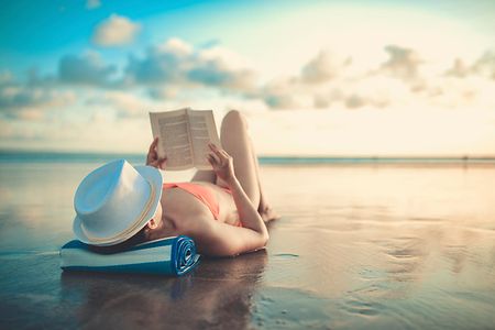 Female Reading and Enjoying Sunset on Beach by the Ocean