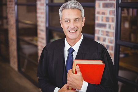Male lawyer standing with red book at office