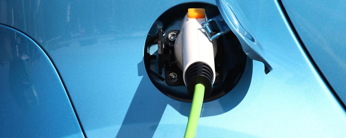 Ein Ladekabel steckt in einem blauen Elektrofahrzeug.