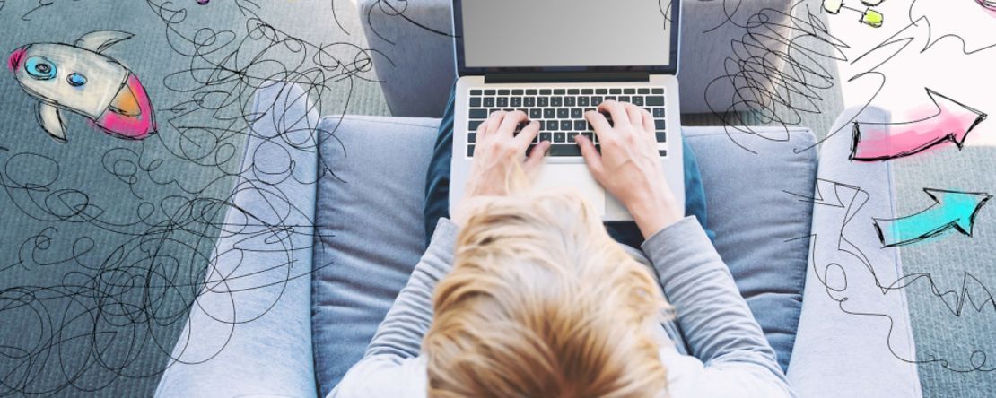 Jugendlicher sitzt mit seinem Laptop auf dem Sessel und tippt etwas ein