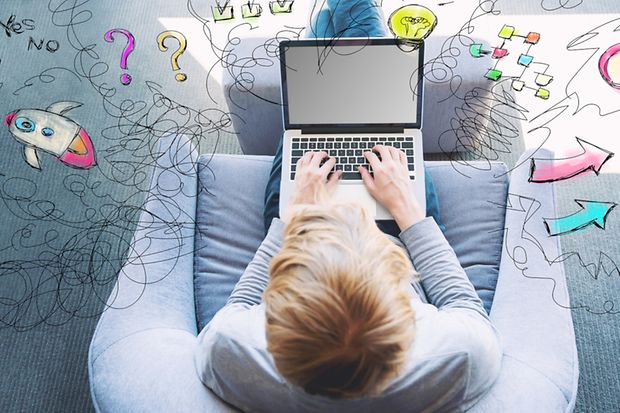 Jugendlicher sitzt mit seinem Laptop auf dem Sessel und tippt etwas ein