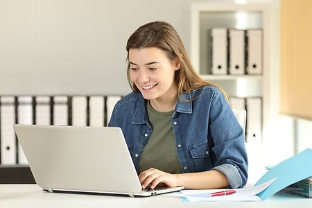 gl&uuml;ckliche junge Frau an ihrem Laptop