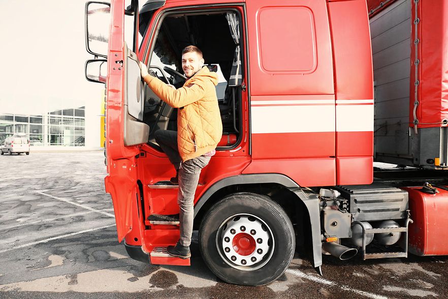 LKW-Fahrer steigt in seinen LKW ein und l&auml;chelt