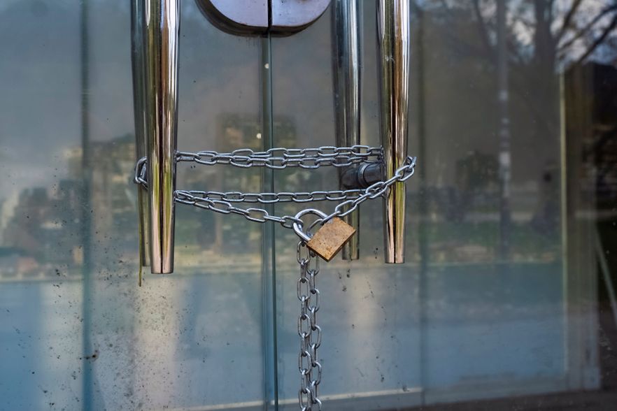 Gro&szlig;aufnahme eines Metallschlosses mit einer silbernen Kette, die am Griff einer Glast&uuml;r h&auml;ngt.