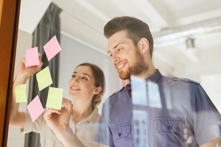 happy creative team writing on stickers at office