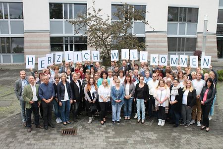Menschenmenge h&auml;lt Schilder mit Aufschrift Herzlich Willkommen hoch
