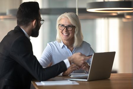 Businessman consulting mature businesswoman client, using laptop