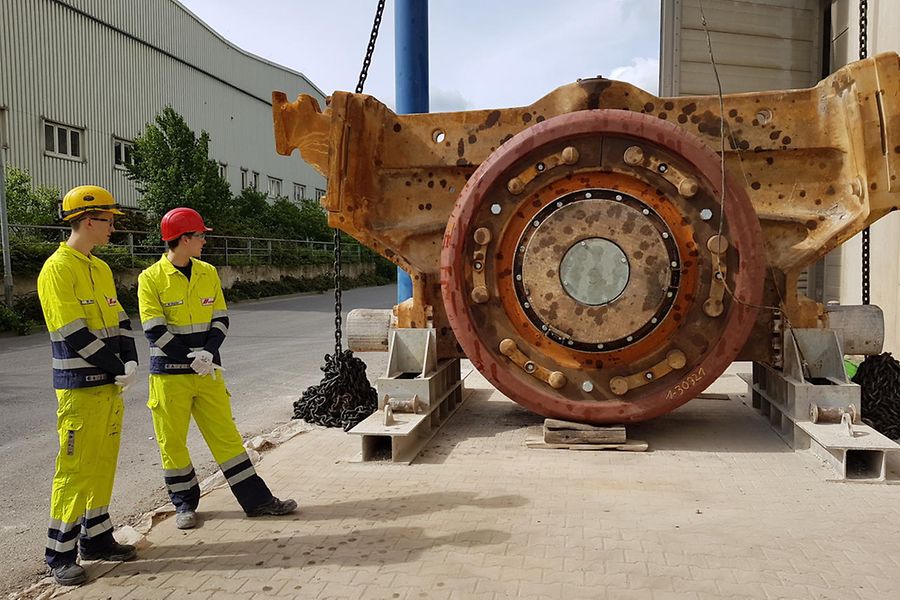 Zwei Arbeiter in gelben Anzügen vor rotbraunem Gerät