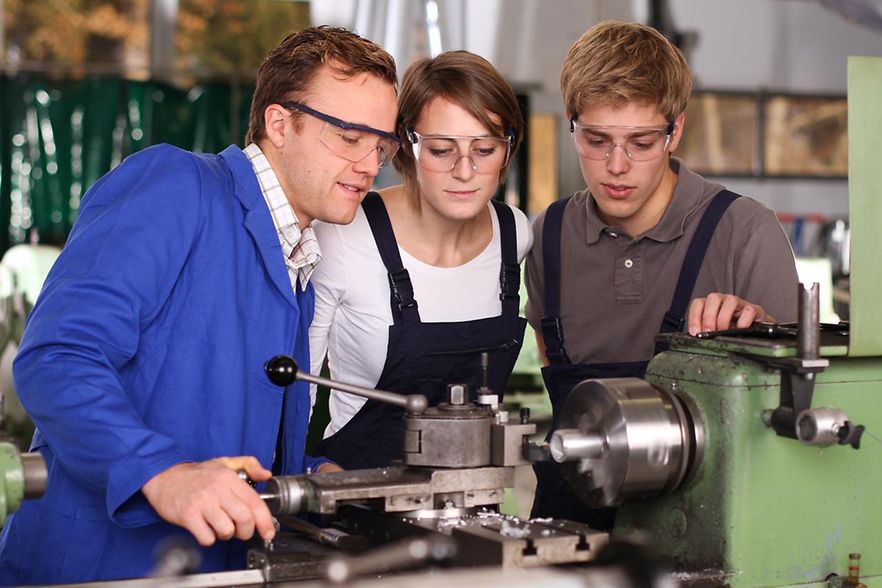 Ausbilder erkl&auml;rt Azubis eine Maschine