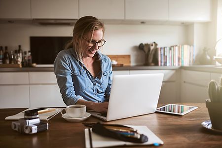 junge Frau mit Laptop an ihrem K&uuml;chentisch
