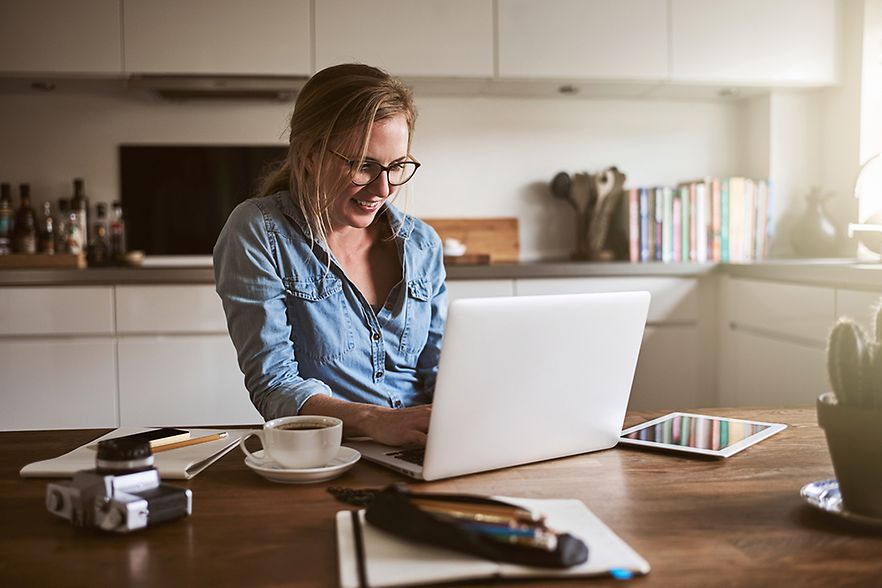junge Frau mit Laptop an ihrem K&uuml;chentisch
