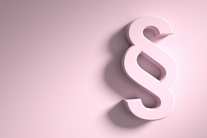 ZU sehen ist ein Paragraf, der sich reliefartig vom rosa Hintergrund abhebt.