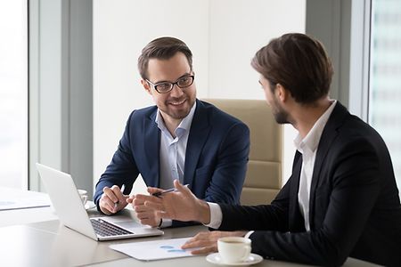 zwei junge M&auml;nner im Gespr&auml;ch vor einem Laptop
