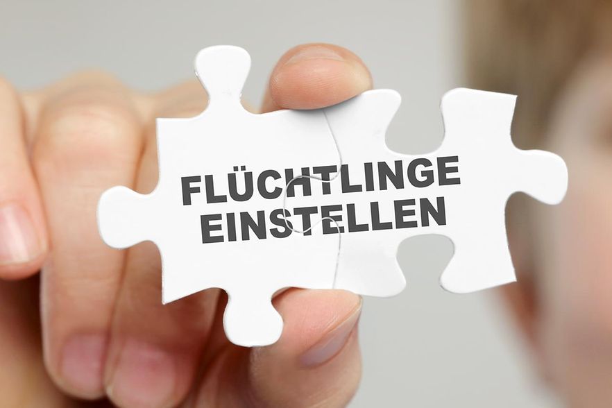 Hand h&auml;lt Puzzle-Teil mit Aufschrift "Fl&uuml;chtlinge einstellen"