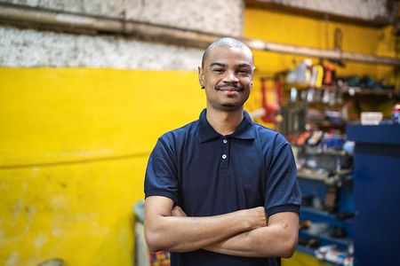Men standing in a auto repair shop with arms crossed