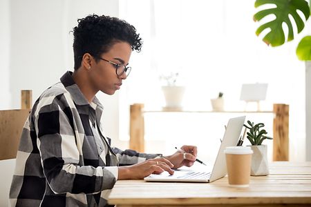 African american young woman using laptop working or studying online