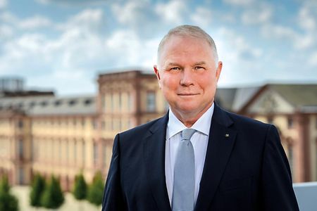 Pr&auml;sident der IHK Rhein-Neckar lacht in die Kamera und steht auf der Terasse