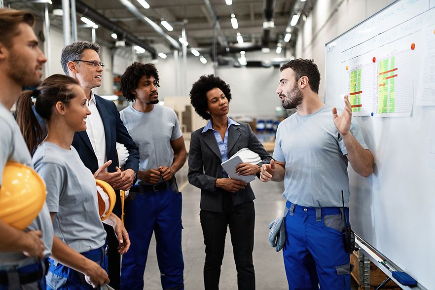 Arbeiter in Fabrik erkl&auml;rt Kolleginnen und Kollegen Projektplan