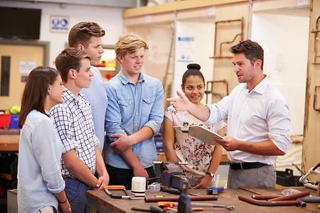 Teacher Helping College Students Studying Plumbing