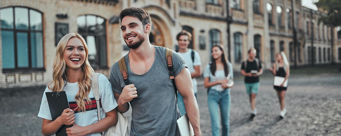 Jugendlichen mit Unterlagen in den H&auml;nden gehen &uuml;ber einen Hof