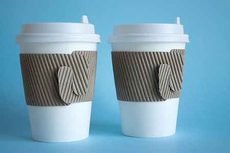 zwei wei&szlig;e Kaffeebecher mit Deckel und Pappbanderole
