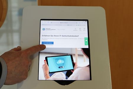 Jens Jankowsky stellt das Portal f&uuml;r IT-Sicherheit vor. Zeigt mit Finger auf Touchscreen-Bildschirm. 