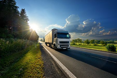 Lastwagen auf Landstra&szlig;e bei Sonnenaufgang