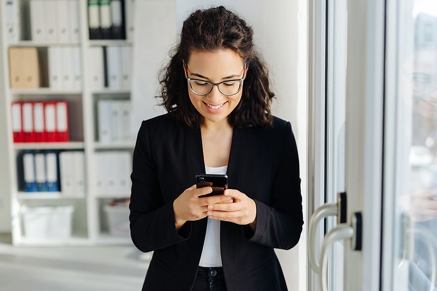 junge Gesch&auml;ftsfrau schaut auf ihr Handy