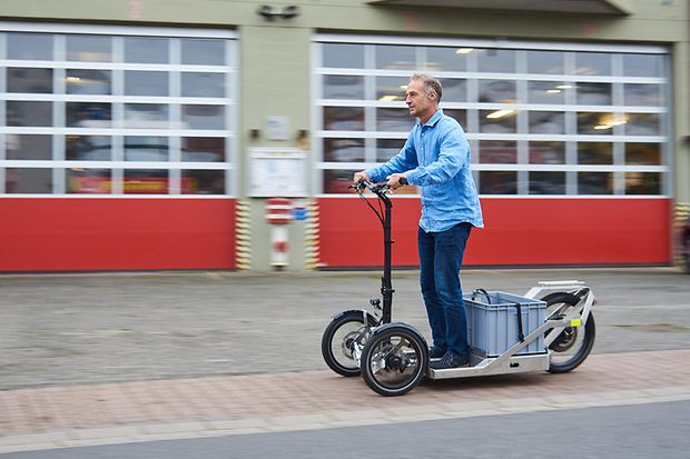 M&auml;nnliche Person f&auml;hrt mit einem elektrischen Lastenroller
