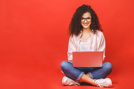 sitzende junge Frau mit Locken, Laptop auf den Knien