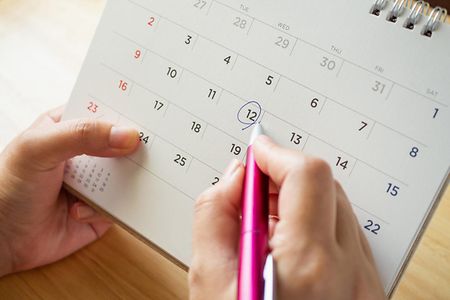 Hand umkreist Datum mit Stift im Kalender