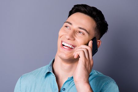 junger Mann telefoniert lachend mit seinem Handy