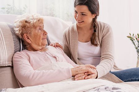 junge Frau k&uuml;mmert sich um pflegebed&uuml;rftige Mutter
