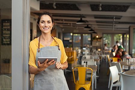 Frau mit Tablet und Sch&uuml;rze in ihrem Caf&eacute;