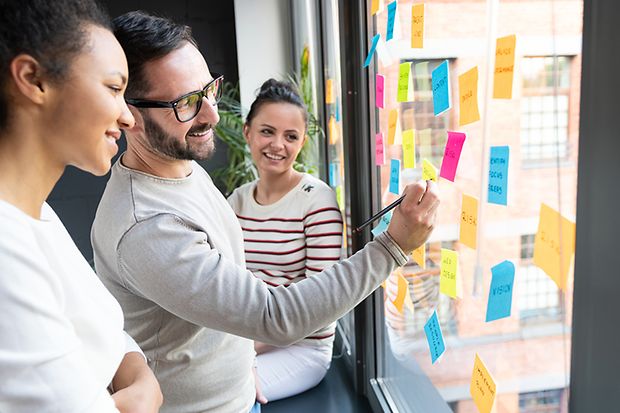 junge Leute kleben Postits ans Fenster