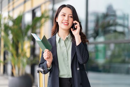 Asiatische Frau h&auml;lt Pass und telefoniert