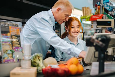 Auszubildende mit Ausbilder an der Supermarktkasse
