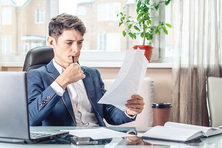 Male Manager sitting at a work place examing documents. Concept of the office working with documents