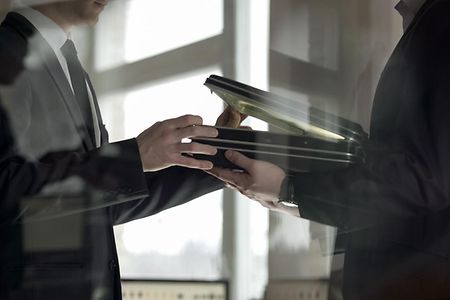 Mann &uuml;bergibt Aktenkoffer mit Geld